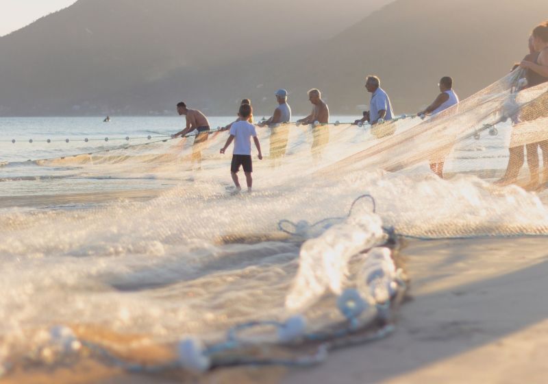 Pessoas usando rede de pesca na beira da praia
